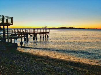 Pier over sea against clear sky during sunset