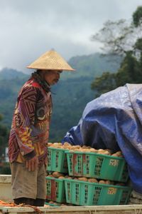 Man working in basket against sky