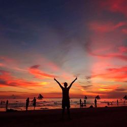 Silhouette people at beach against sky during sunset