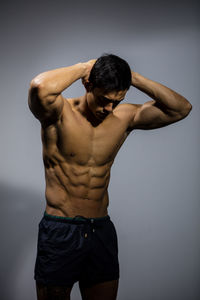 Full length of shirtless man standing against gray background