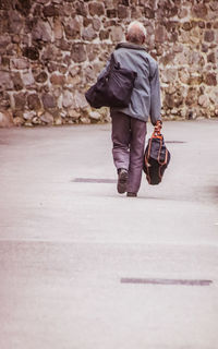 Rear view of man walking on footpath