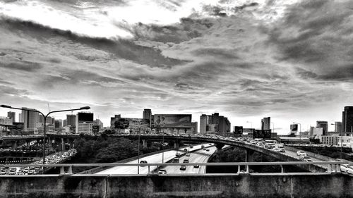 Bridge and buildings against cloudy sky in city