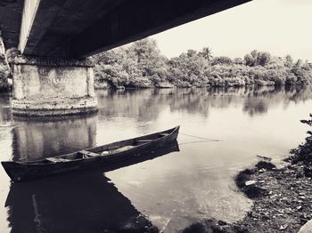 Boat in river by trees against sky