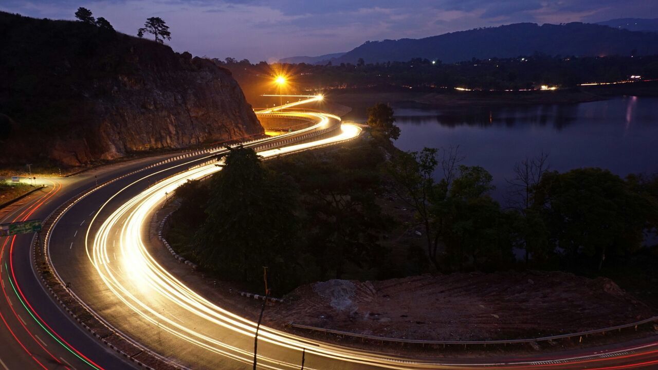 LIGHT TRAILS ON ROAD IN CITY AT NIGHT