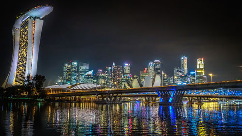 Illuminated marina bay sands by river against sky at night