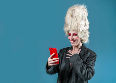 Young woman using mobile phone against blue background