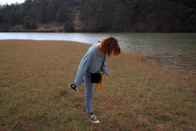 Full length of young woman standing by lake