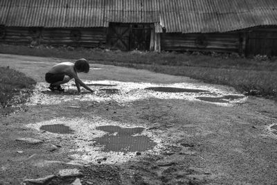 Side view of a boy playing with rain puddle