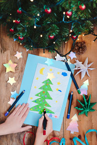 Woman making greeting card of christmas decoration on table