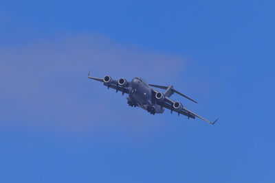 Low angle view of airplane flying against clear blue sky