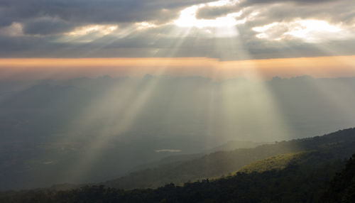 Sunlight streaming through clouds over landscape