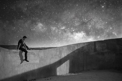 Man sitting against sky at night