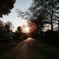 Road amidst trees against sky during sunset