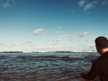 Rear view of man on beach against sky