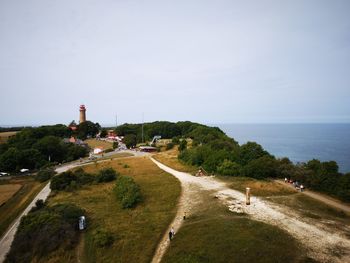 Road by sea and buildings against sky