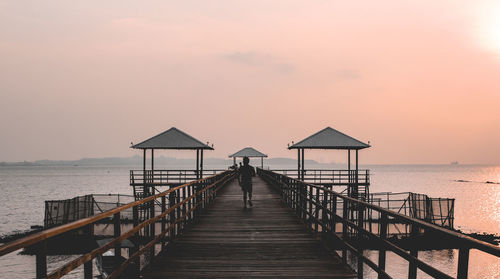 Pier over sea against sky during sunset