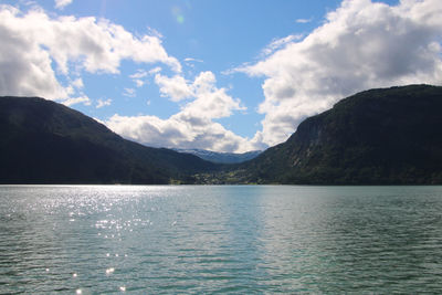 Scenic view of lake by mountains against sky