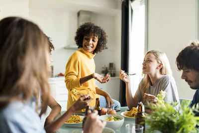 Friends sitting at table talking, eating and drinking beer