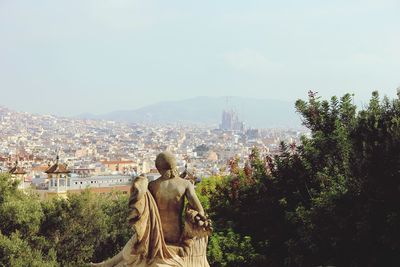 Statue by trees and buildings against sky