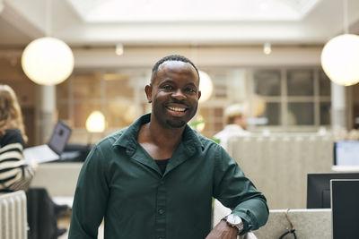 Portrait of smiling male creative professional near desk in office