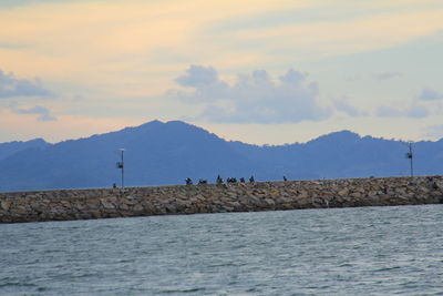 Scenic view of sea by mountains against sky