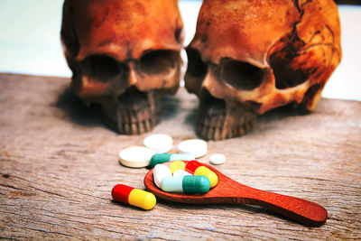 Close-up of wooden spoon with pills and human skulls on table