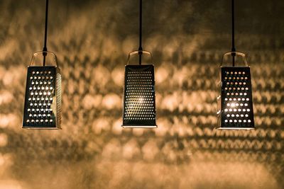 Close-up of illuminated lighting equipment hanging against wall