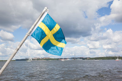 Close-up of swedish flag blowing against sea