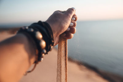 Midsection of man holding sand at beach against sky