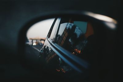 Reflection of man photographing car on side-view mirror