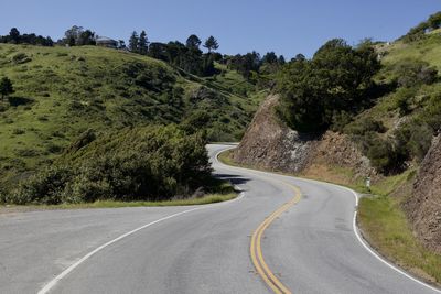 Empty road amidst trees against sky
