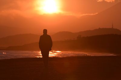 Rear view of a silhouette man overlooking calm lake