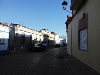 Cars on street in city against clear sky