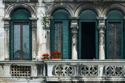 Ancient vintage balcony in venice, italy. venetian architecture. red flower in a pots at  balcony