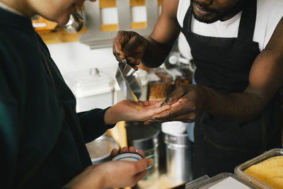 Owner pouring food in hand of customer at sustainable store