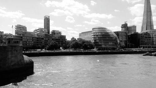 Modern buildings by river against sky in city