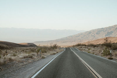 Road leading towards mountains against sky