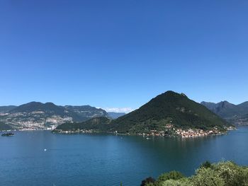 Scenic view of sea and mountains against clear blue sky