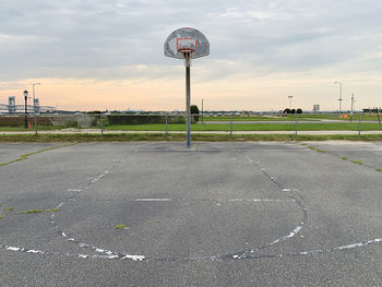 View of empty basketball court against sky and tiny new york city skyline on the horizon