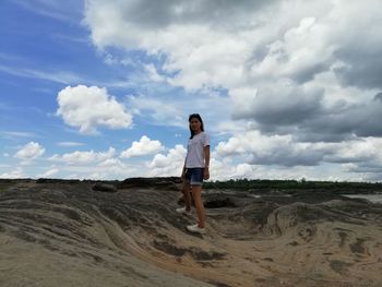 Portrait of woman standing on rock against sky