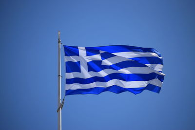 Low angle view of flag against blue sky