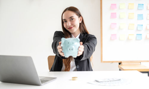 Portrait of young woman using mobile phone while sitting on table