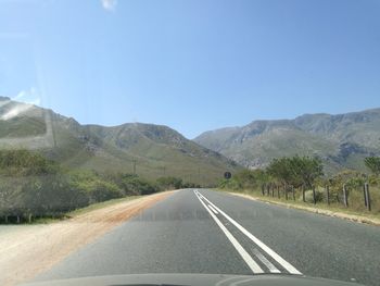 Road leading towards mountains against sky