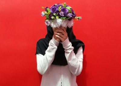 Woman standing against red wall