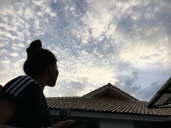 Low angle view of man outside house against sky