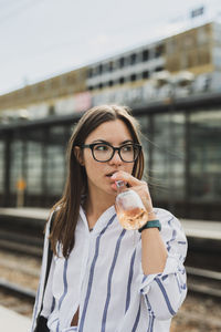 Portrait of young woman holding ice cream in city
