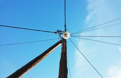 Low angle view of electricity pylon against blue sky