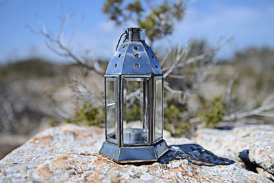 Close-up of old lantern on field against sky