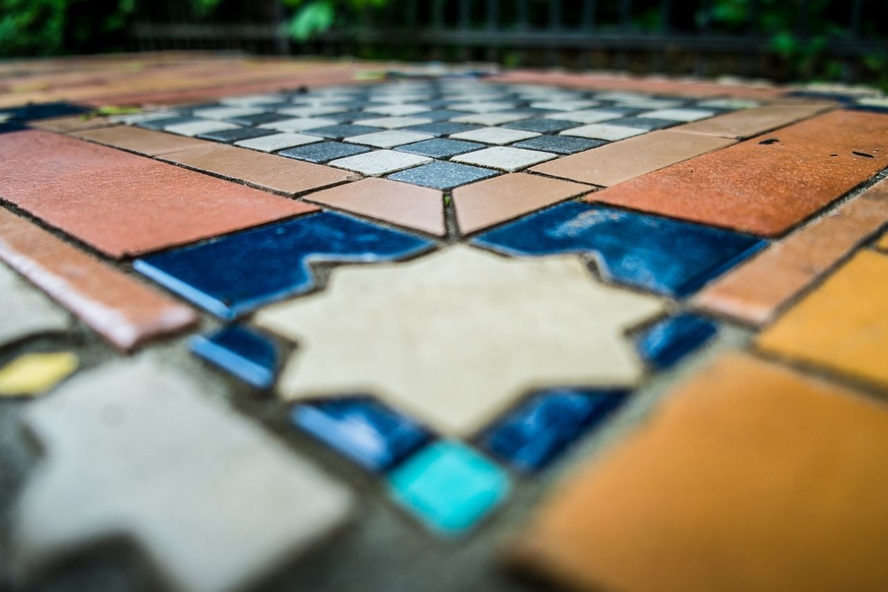 selective focus, focus on foreground, surface level, close-up, high angle view, day, in a row, outdoors, sunlight, street, no people, metal, shadow, empty, focus on background, pattern, blue, absence, footpath, multi colored