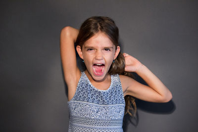 Portrait of girl standing against gray background